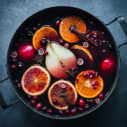 overhead view of spiced citrus and pear mulled wine in a large pot on blue backdrop.