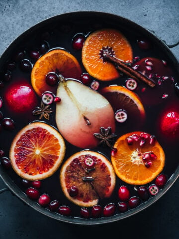 overhead view of spiced citrus and pear mulled wine in a large pot on blue backdrop.