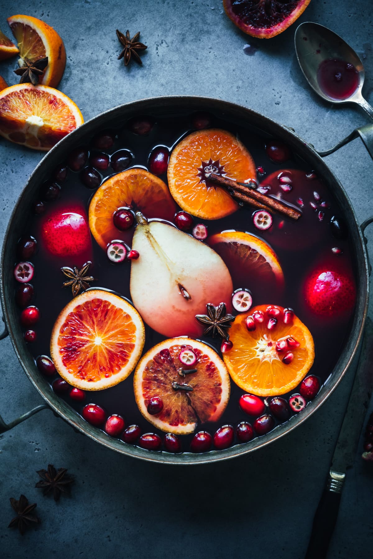 overhead view of spiced citrus and pear mulled wine in a large pot on blue backdrop. 
