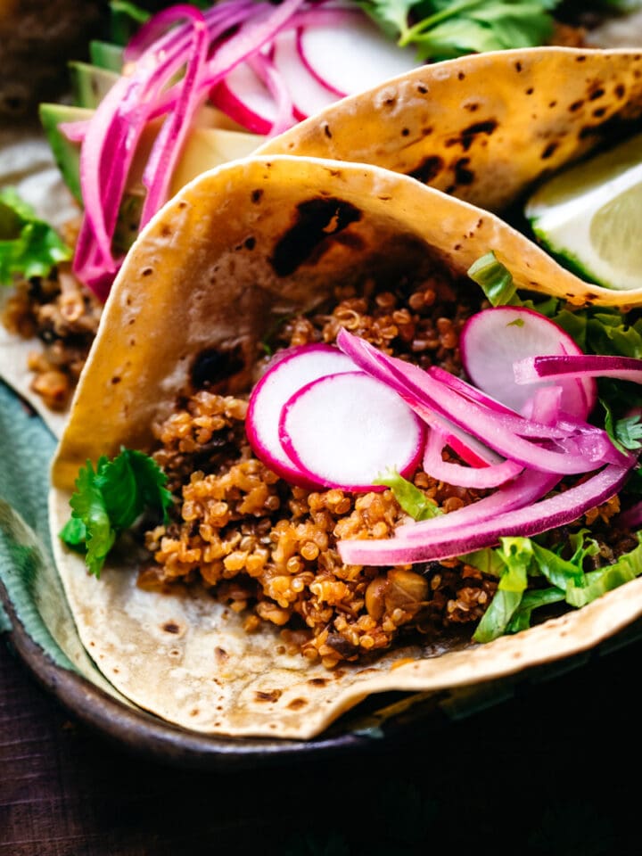 close up view of taco with vegan cauliflower quinoa taco meat and pickled onion.