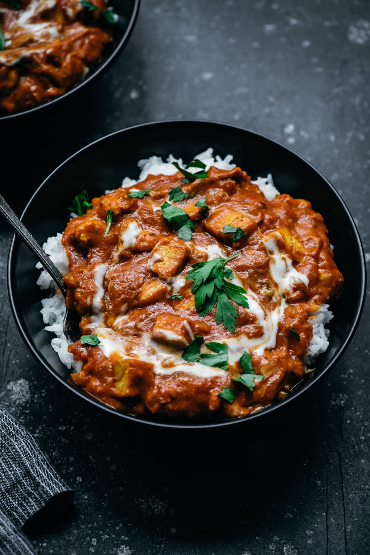 side view of vegan tofu tikka masala in a bowl with white rice. 