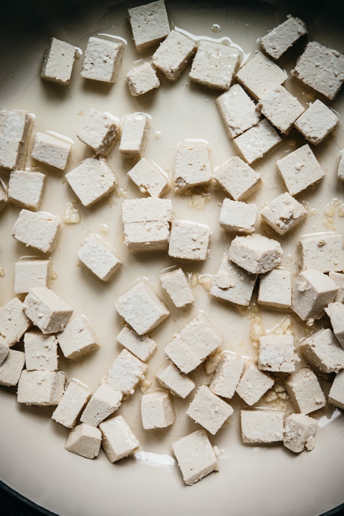 close up view of uncooked tofu in a pan. 