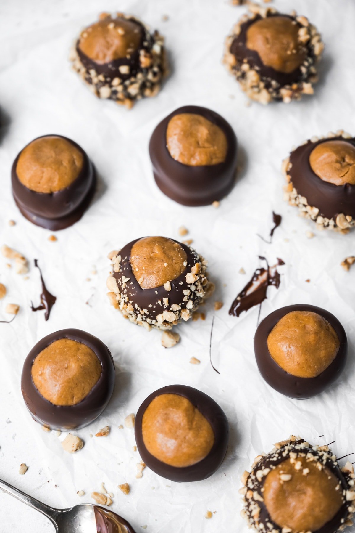 side view of chocolate dipped peanut butter vegan buckeyes on parchment paper. 