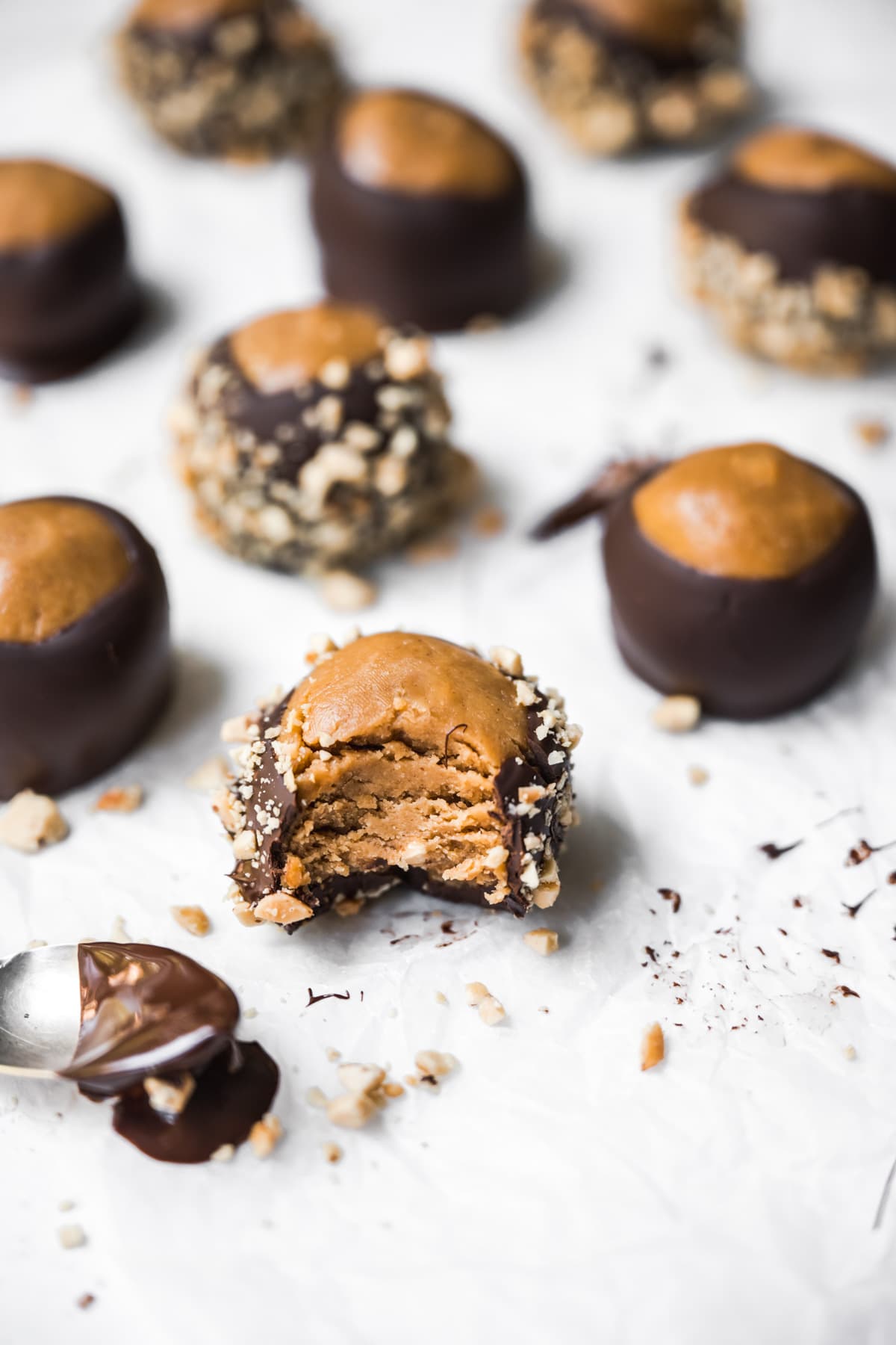 side view of chocolate dipped peanut butter vegan buckeyes on parchment paper. 