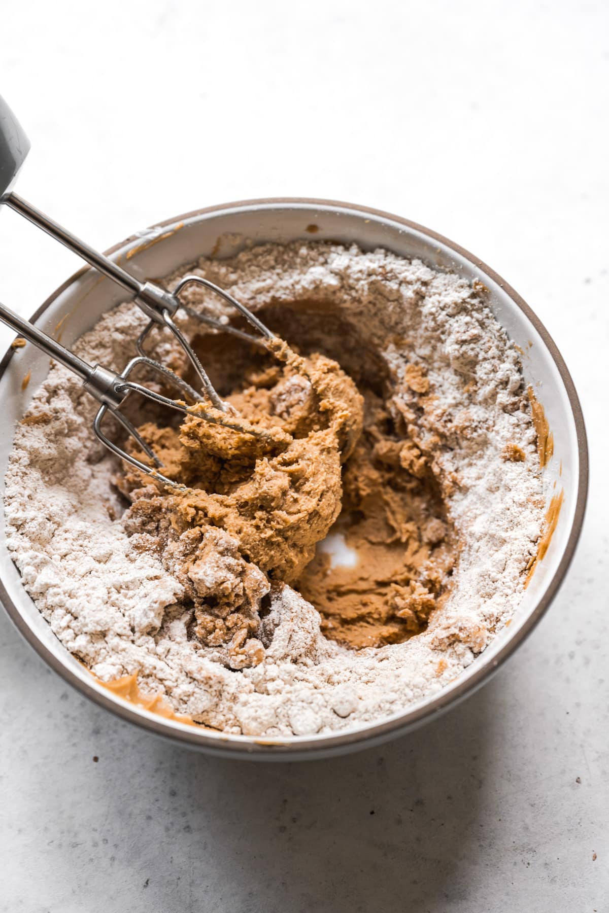 flour and peanut butter mixture being combined in mixing bowl with electric mixer. 