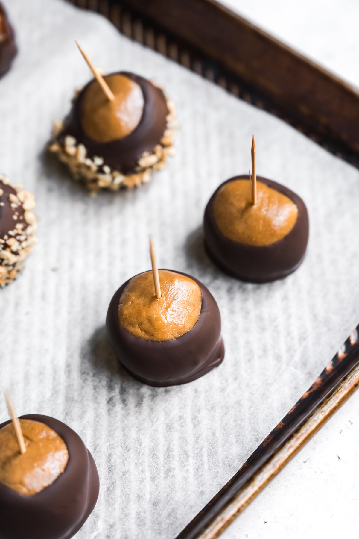 buckeyes on parchment paper with toothpick inserted in top. 