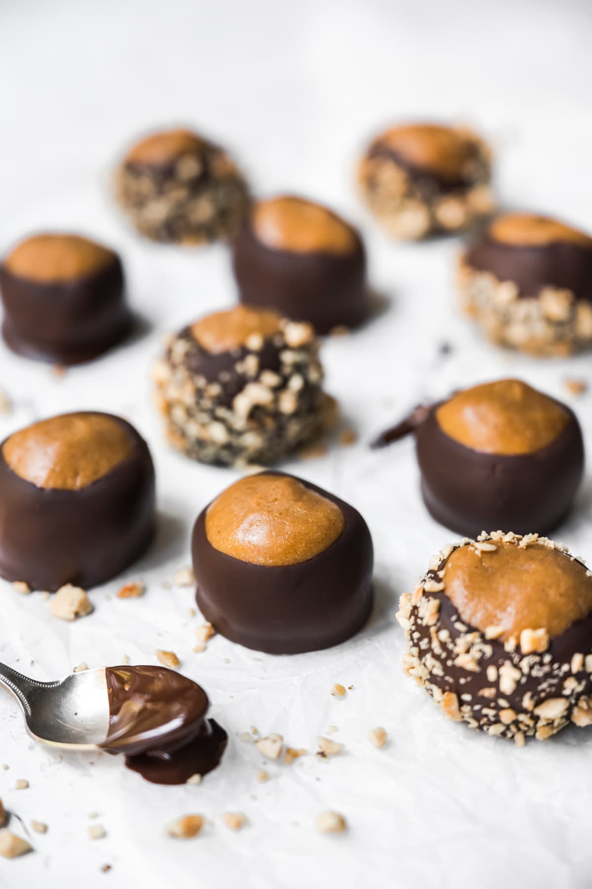 side view of chocolate dipped peanut butter vegan buckeyes on parchment paper. 