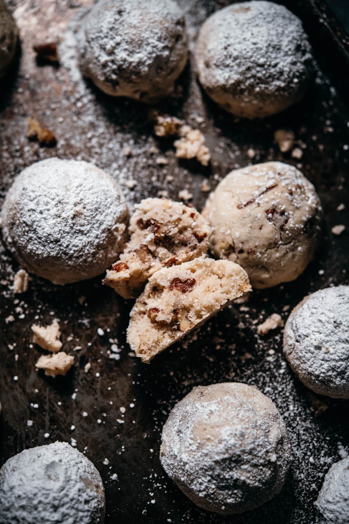 vegan and gluten free pecan snowball cookies with one broken in half to show interior. 