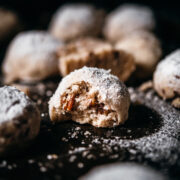 close up view of vegan pecan snowball cookie with bite taken out.