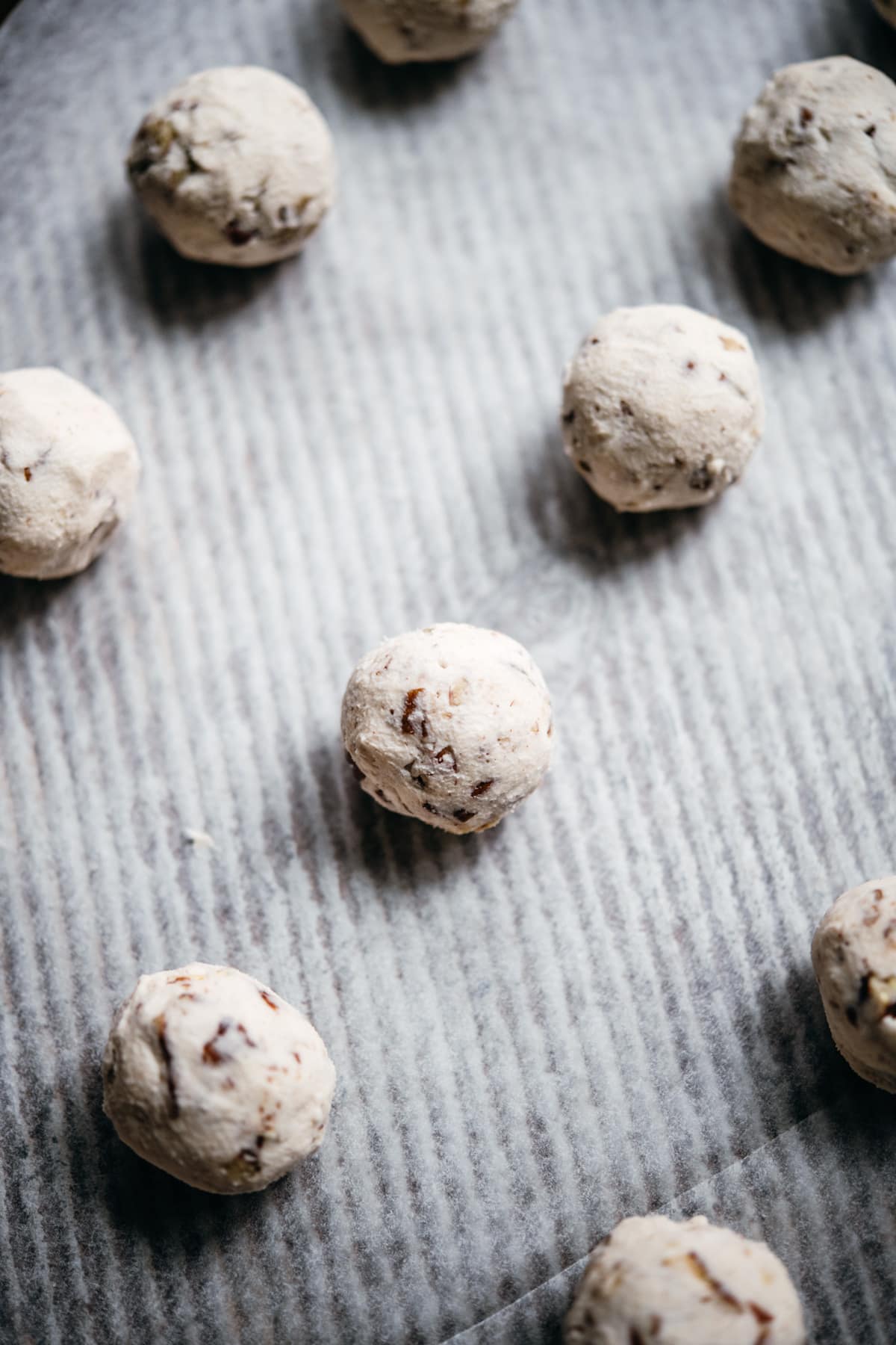 snowball cookie dough balls on parchment paper before baking