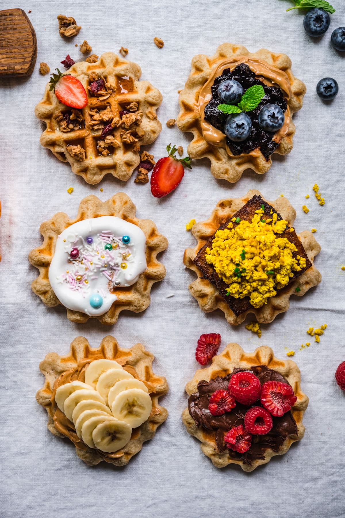 overhead view of 6 homemade waffles with different toppings.