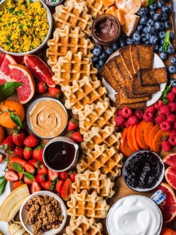 overhead view of loaded build your own waffle board with homemade waffles, fruit and toppings.