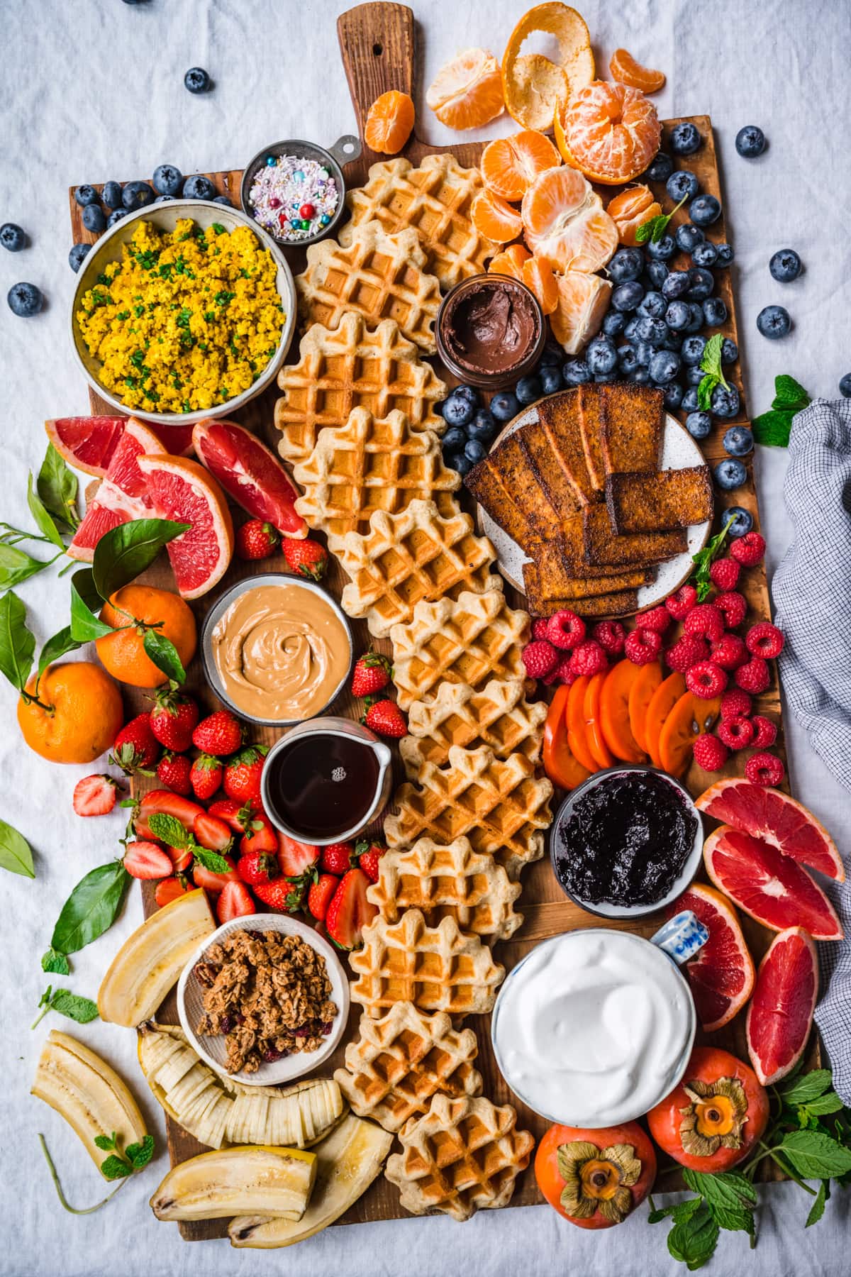 overhead view of loaded build your own waffle board with  homemade waffles, fruit and toppings. 