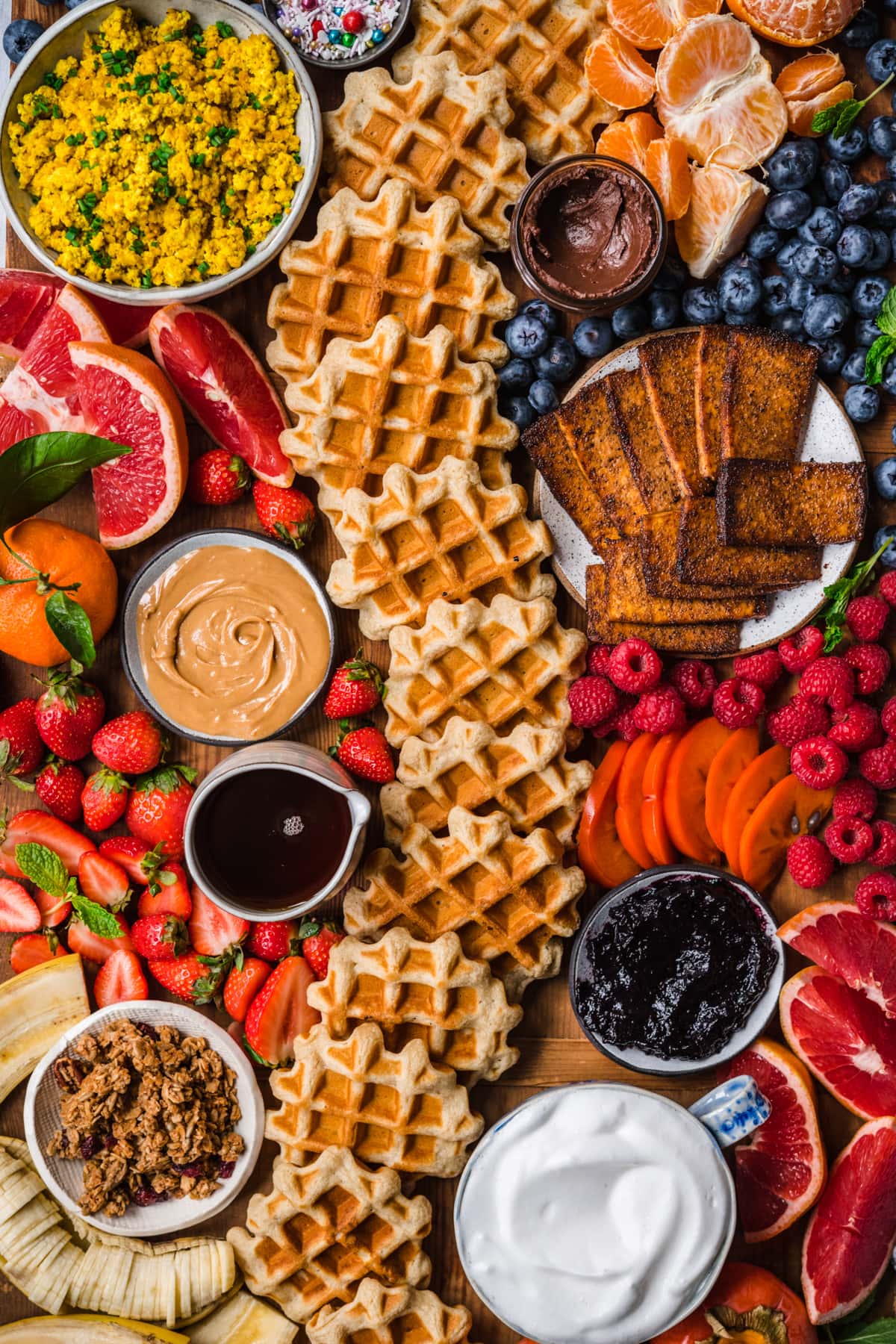 overhead view of loaded build your own waffle board with  homemade waffles, fruit and toppings. 