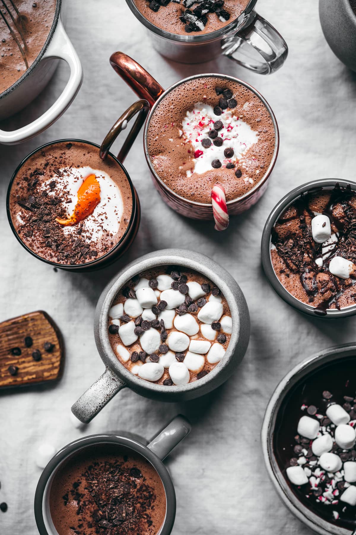 overhead view of vegan hot cocoa 5 ways in different mugs. 