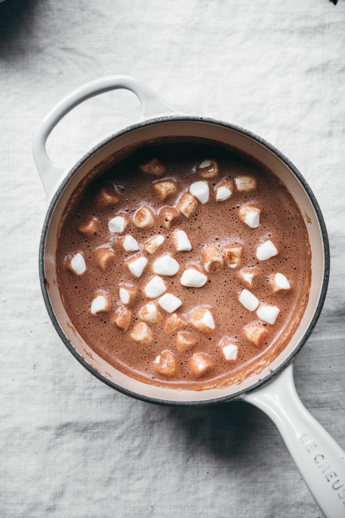 vegan hot chocolate in white saucepan topped with mini marshmallows.