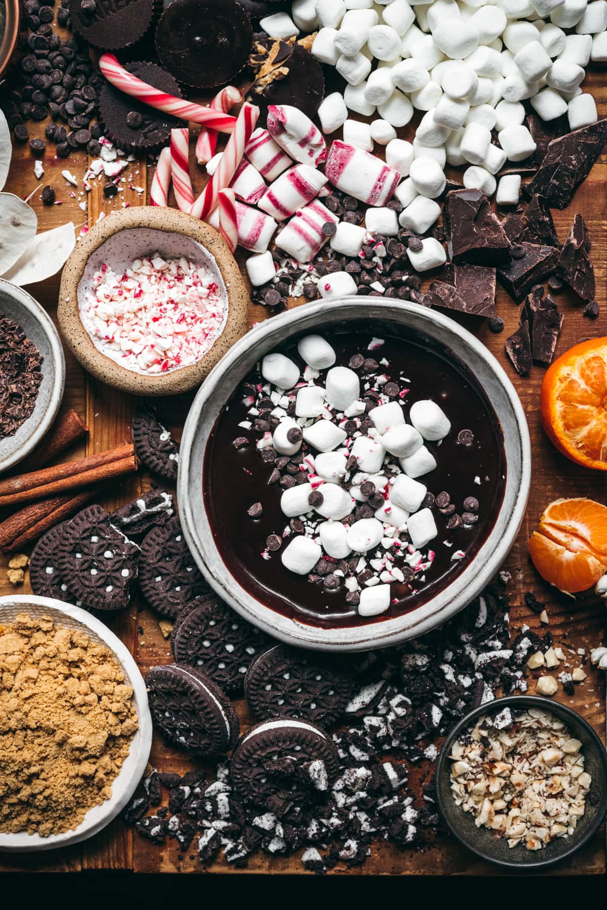 overhead view of hot cocoa board with lots of toppings like chocolate, marshmallows, peppermint, cookies, etc. 