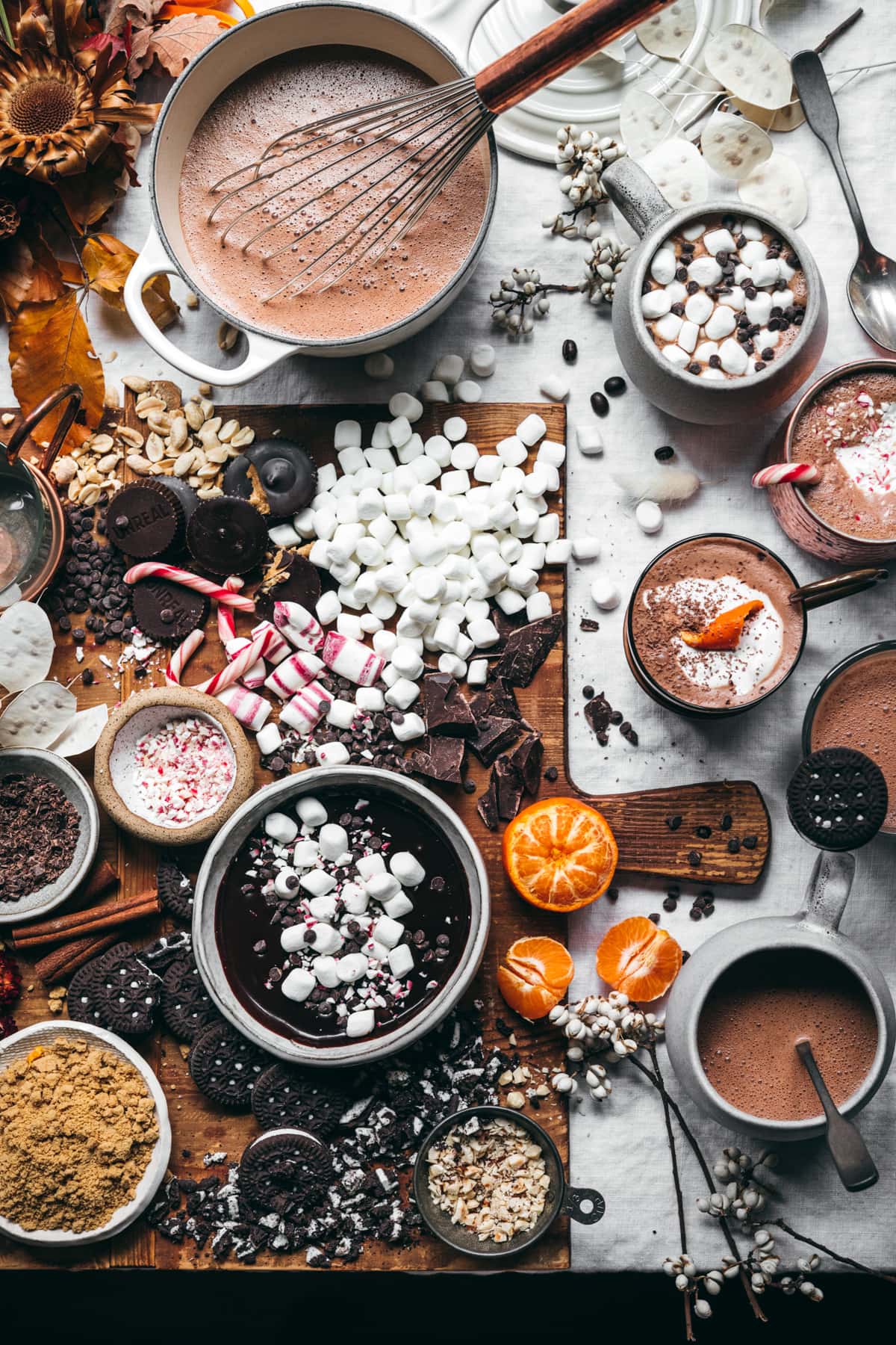 overhead view of hot cocoa board with lots of toppings and mugs of hot chocolate. 