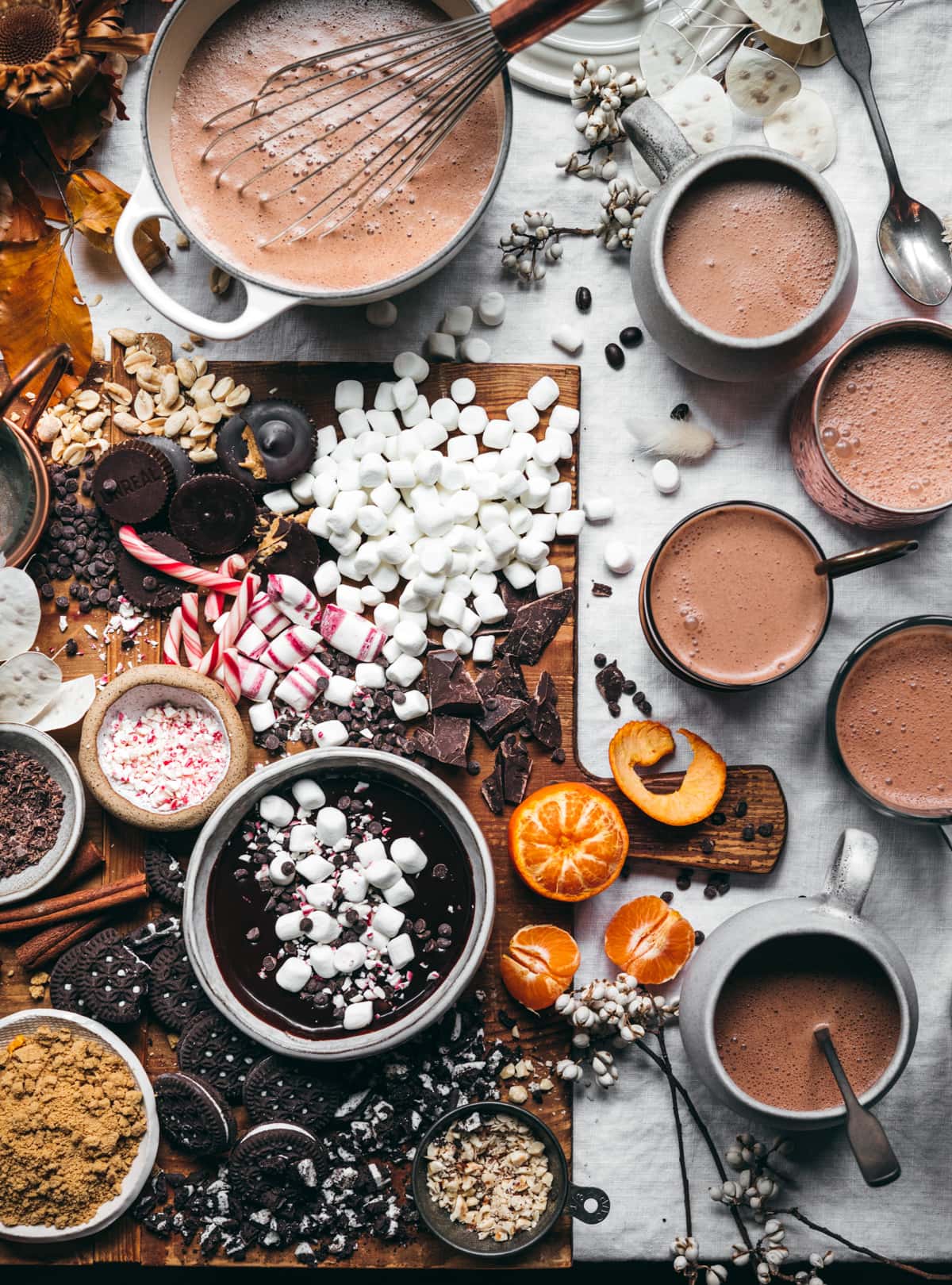 overhead view of hot cocoa board with lots of toppings and mugs of hot chocolate. 