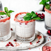 close up side view of vegan peppermint white russian cocktail with candy cane rim and fresh mint garnish.