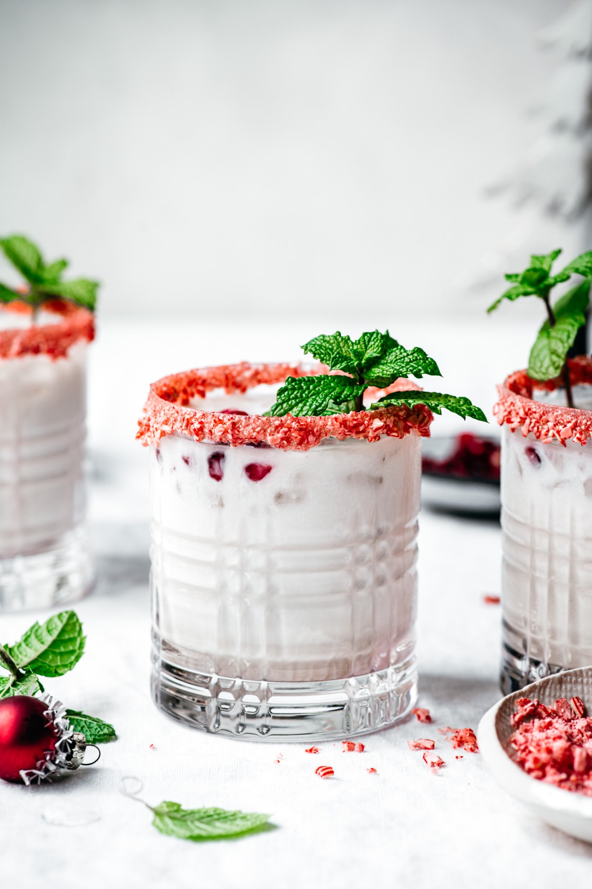 close up side view of vegan peppermint white russian cocktail with candy cane rim and fresh mint garnish. 