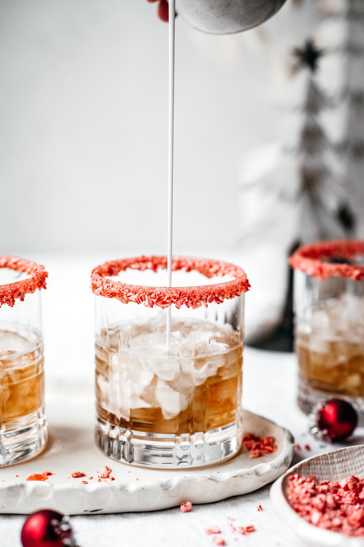 pouring cream into white russian cocktail with candy cane rim.