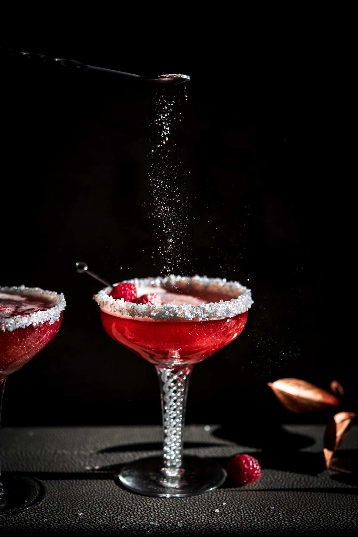 shimmer dust falling on a raspberry rosé santa baby holiday cocktail in antique coupe glass. 