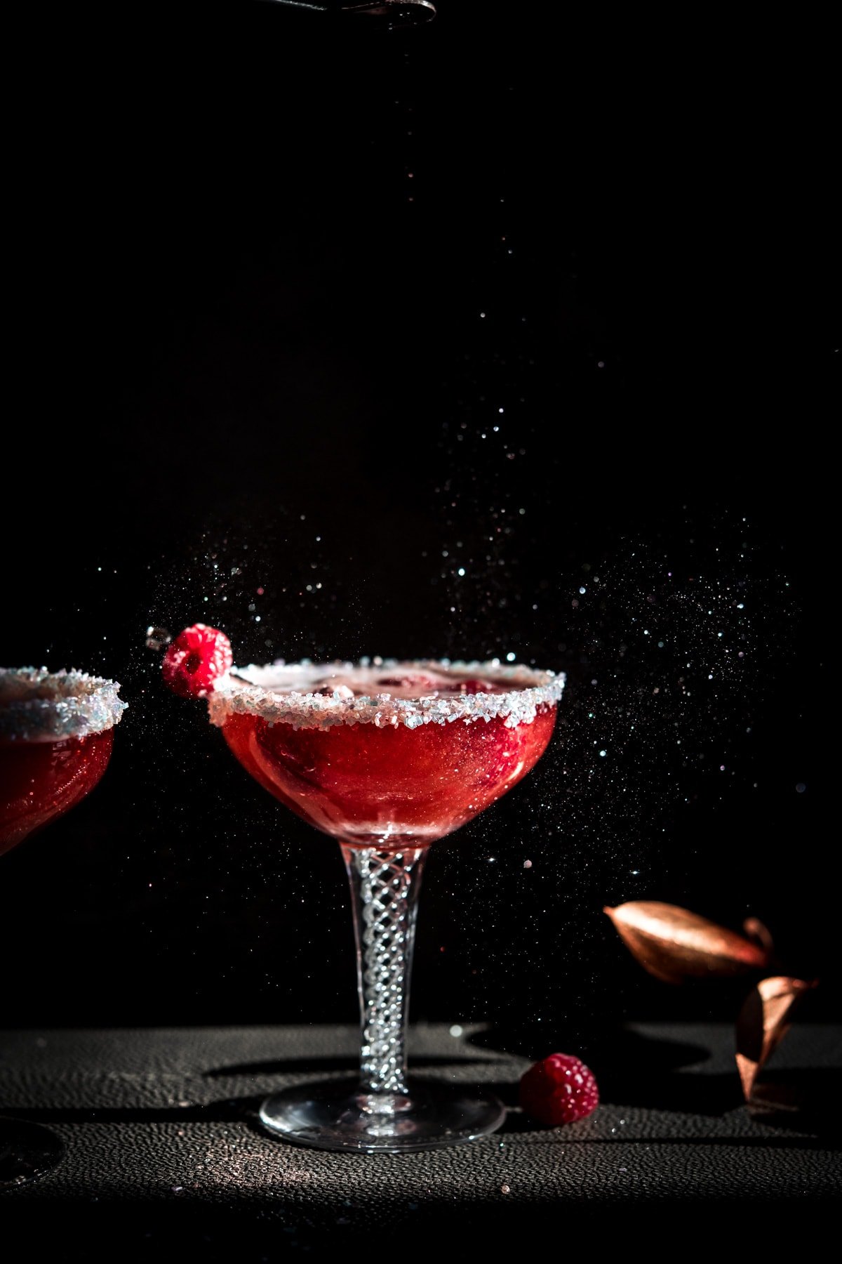 shimmer dust falling on a raspberry rosé santa baby holiday cocktail in antique coupe glass. 