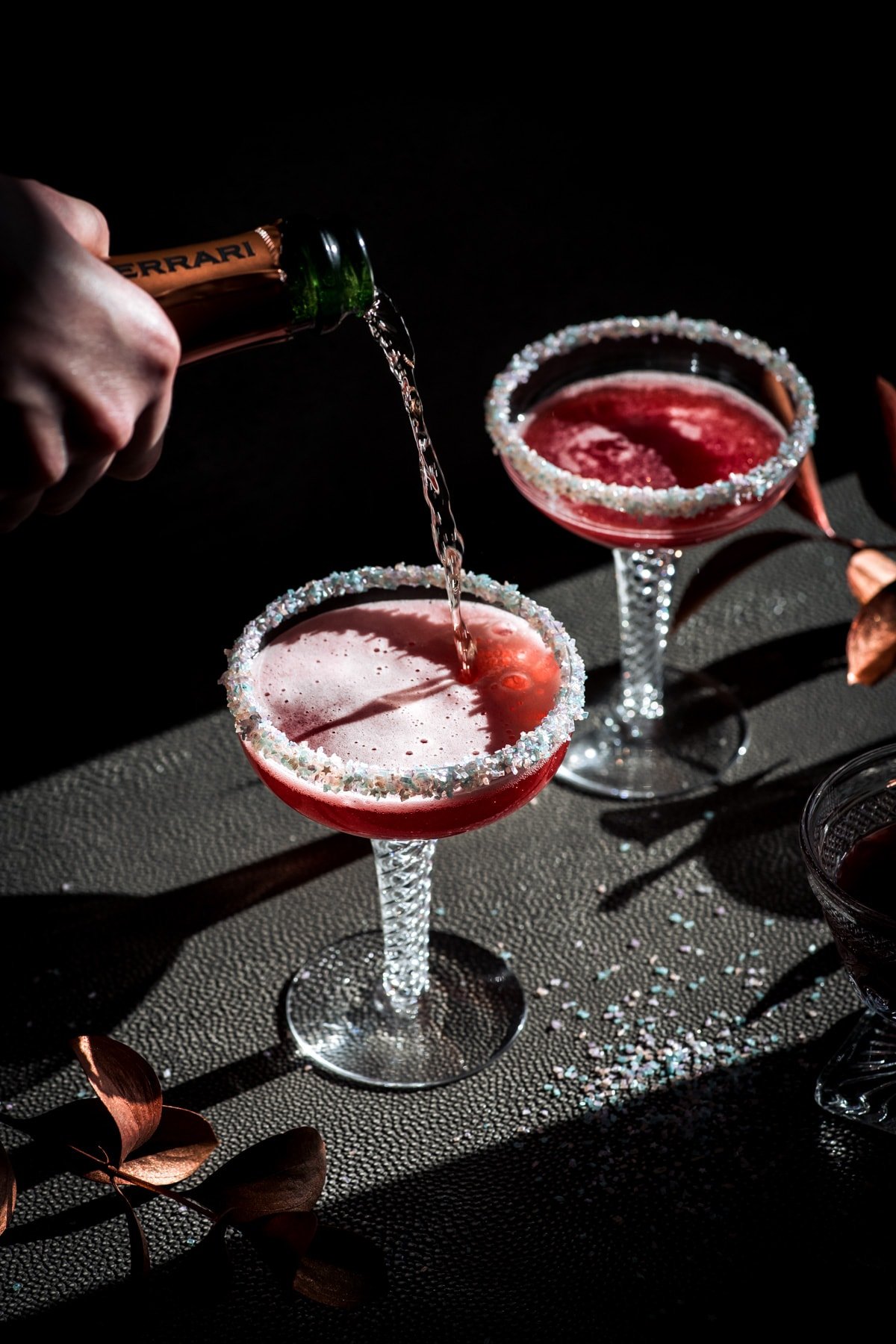 close up side view of pouring champagne into santa baby cocktail.