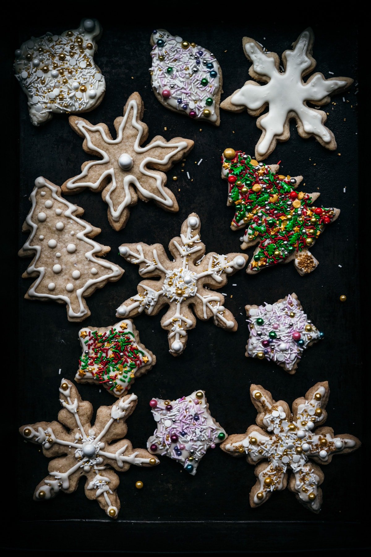 overhead view of sugar cookies in snowflake, christmas tree and star shapes. 