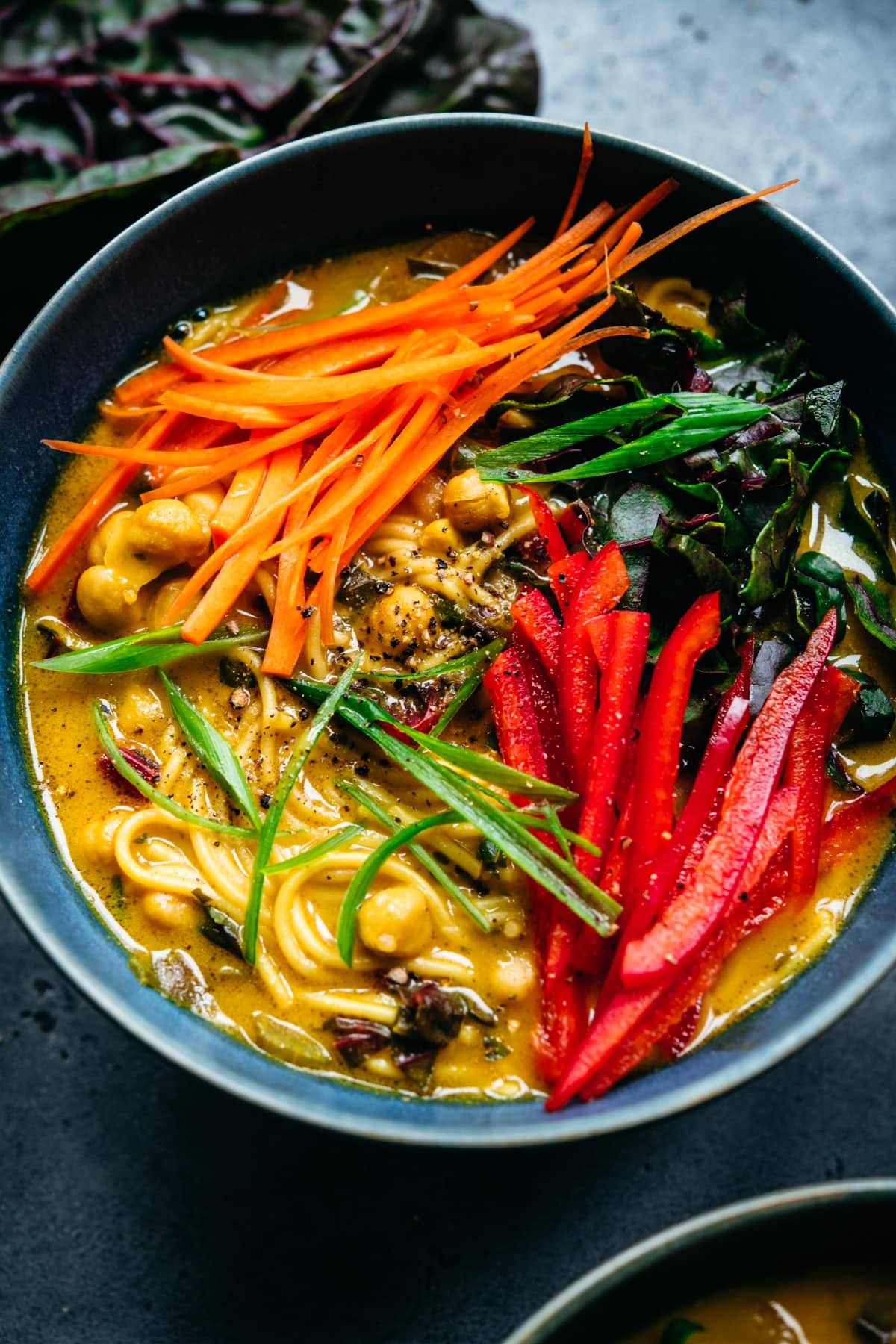 close up view of immune boosting turmeric chickpea noodle soup in a blue soup bowl. 