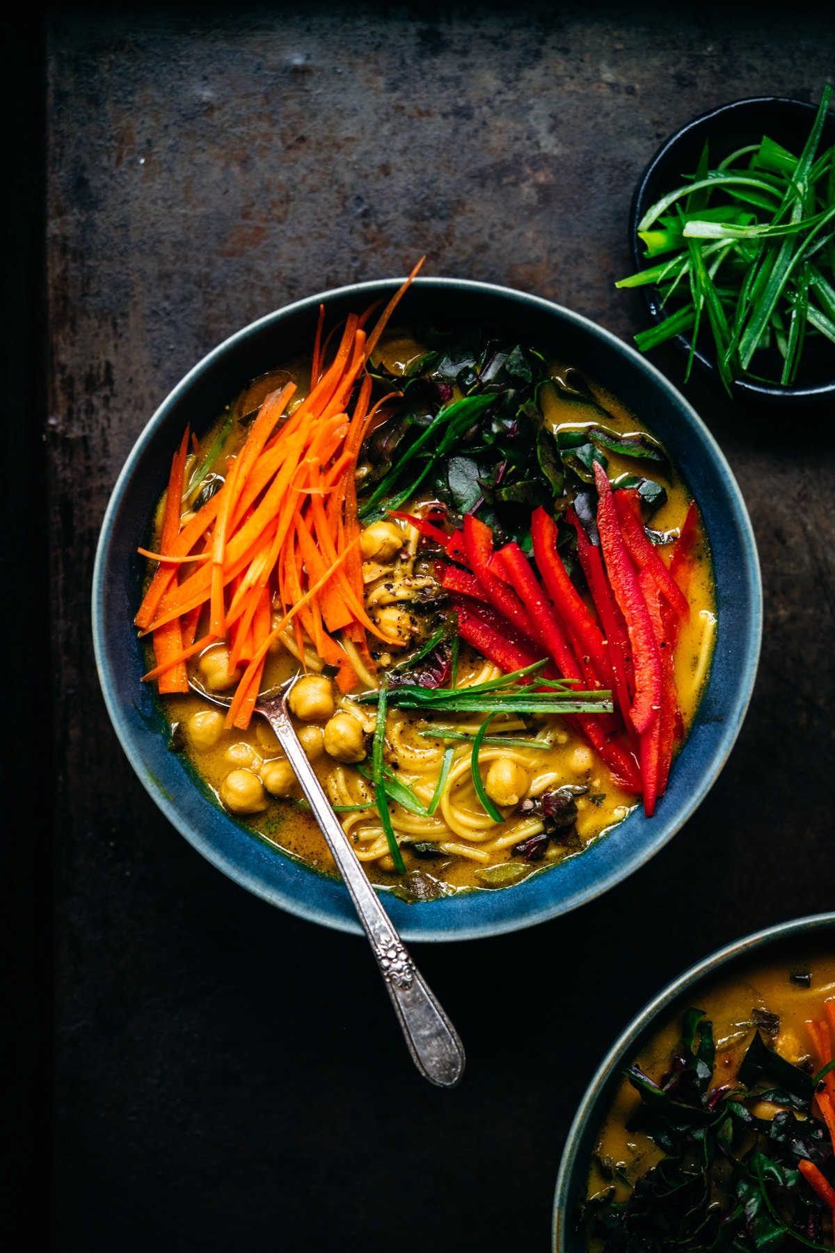 overhead view of immune boosting turmeric chickpea noodle soup in a blue soup bowl. 