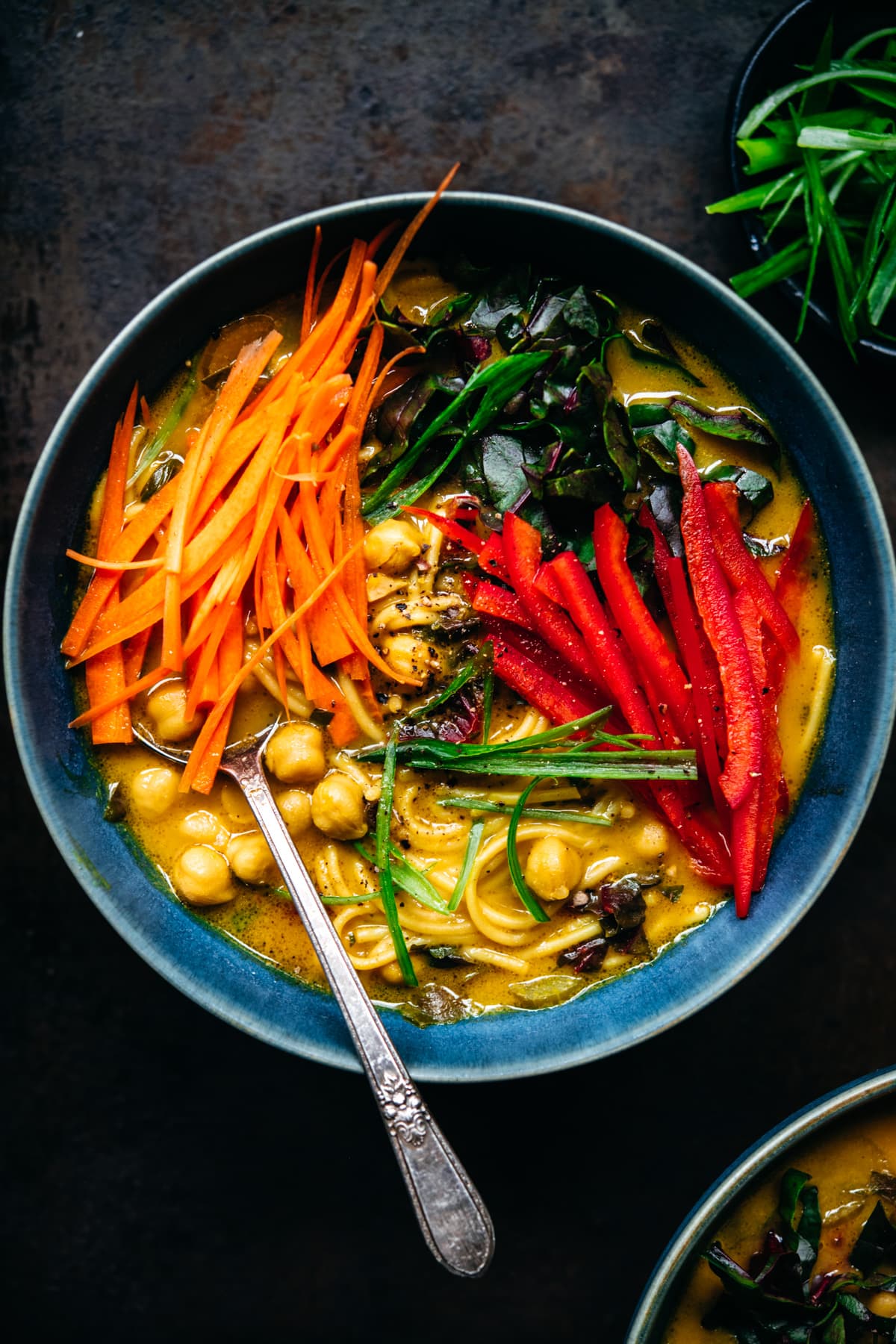 overhead view of immune boosting turmeric chickpea noodle soup in a blue soup bowl. 