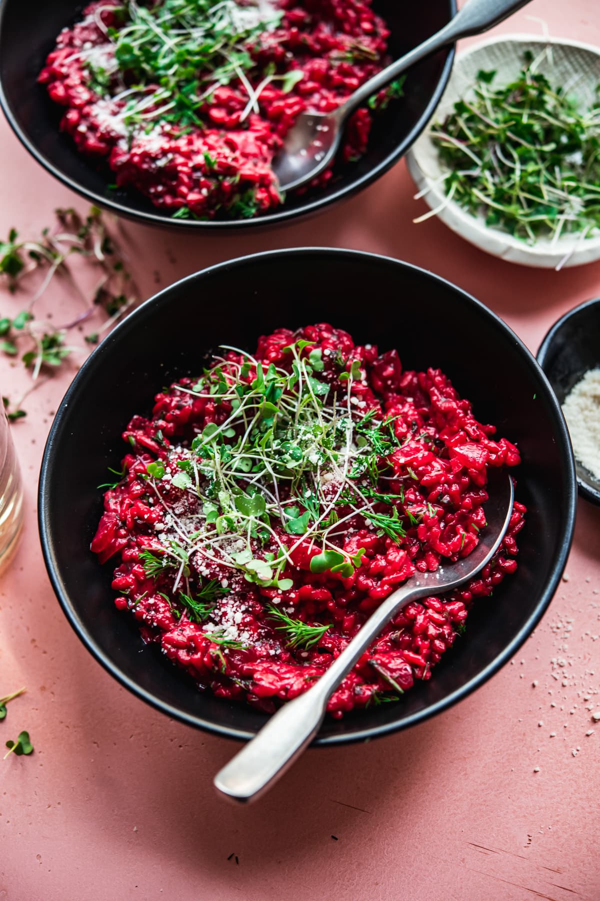 close up view of vegan beet risotto topped with microgreens and vegan parmesan.