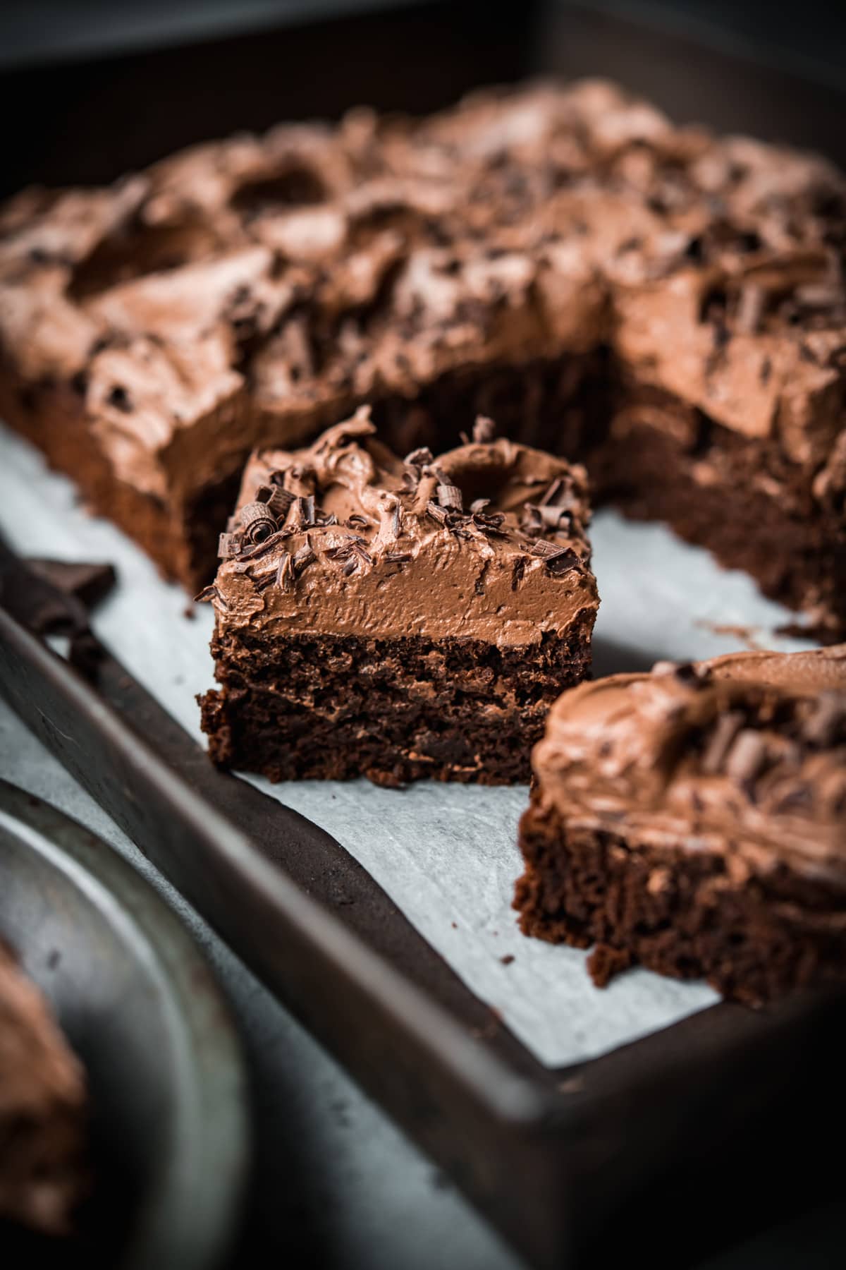 side view of a slice of vegan gluten free chocolate cake with thick layer of frosting. 