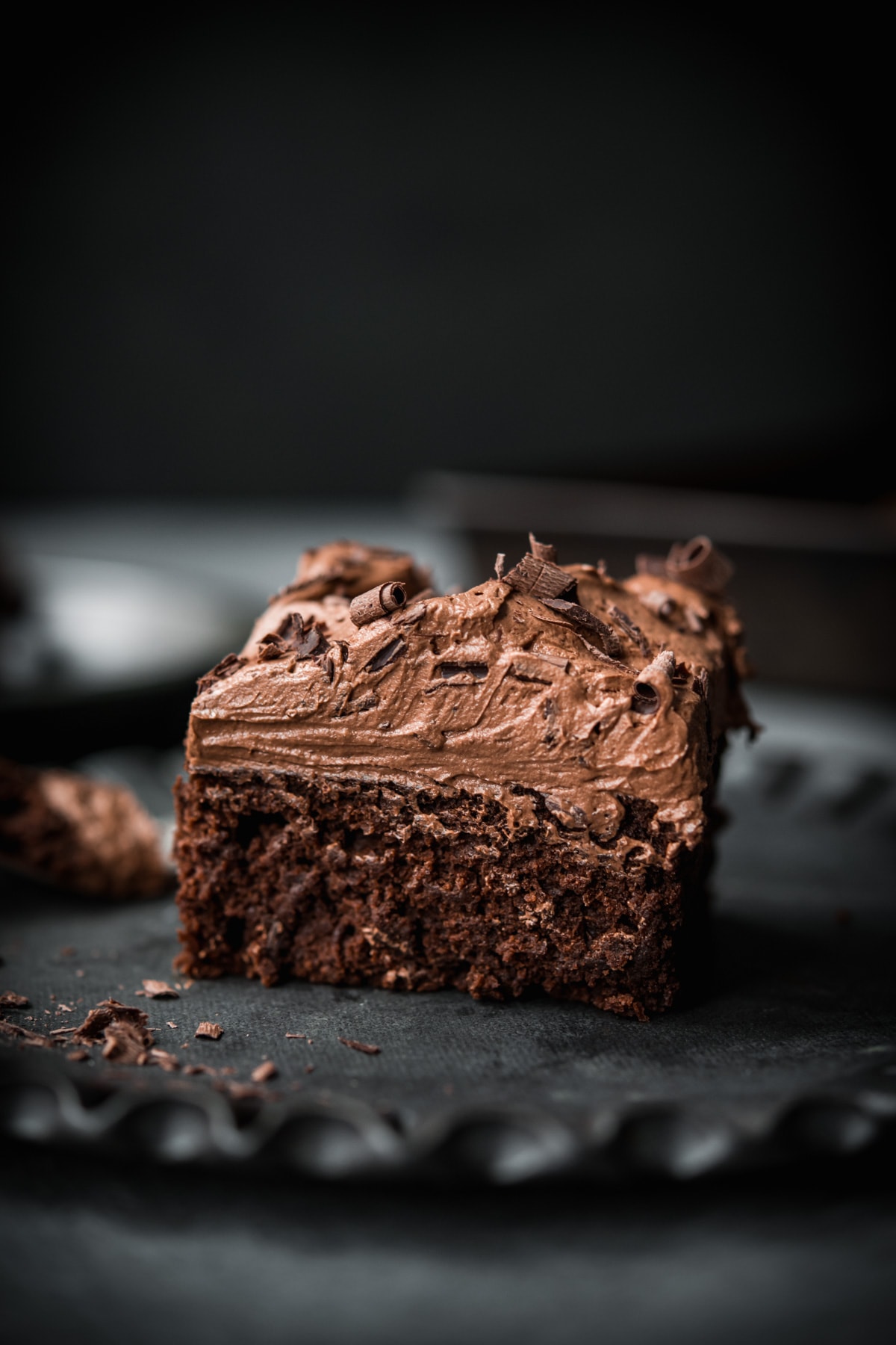 side view of a slice of vegan gluten free chocolate cake with thick layer of frosting. 