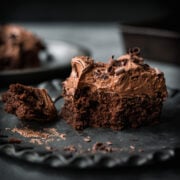 side view of a slice of vegan gluten free chocolate cake with thick layer of frosting.