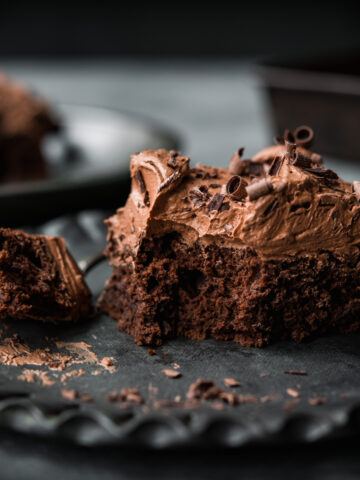 side view of a slice of vegan gluten free chocolate cake with thick layer of frosting.