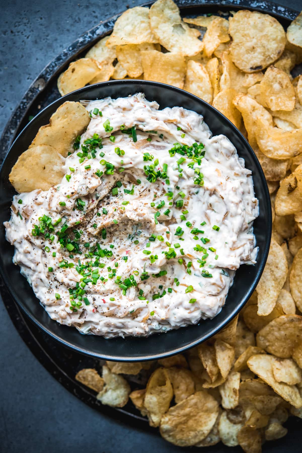 close up view of caramelized onion dip in a bowl with chips. 