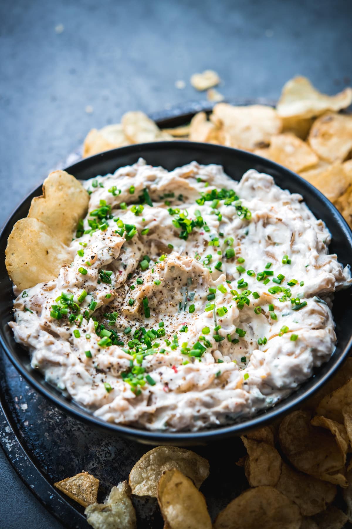 close up view of caramelized onion dip in a bowl with chips. 