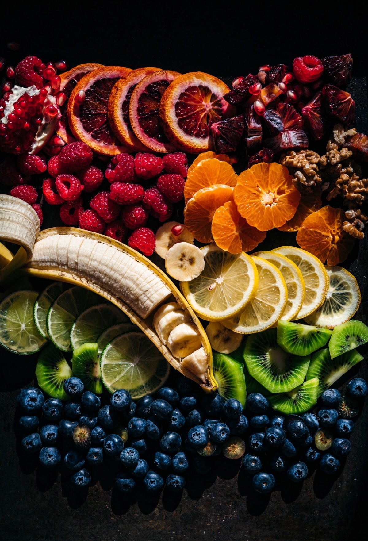 overhead view of rainbow of fresh fruits arranged on a platter.