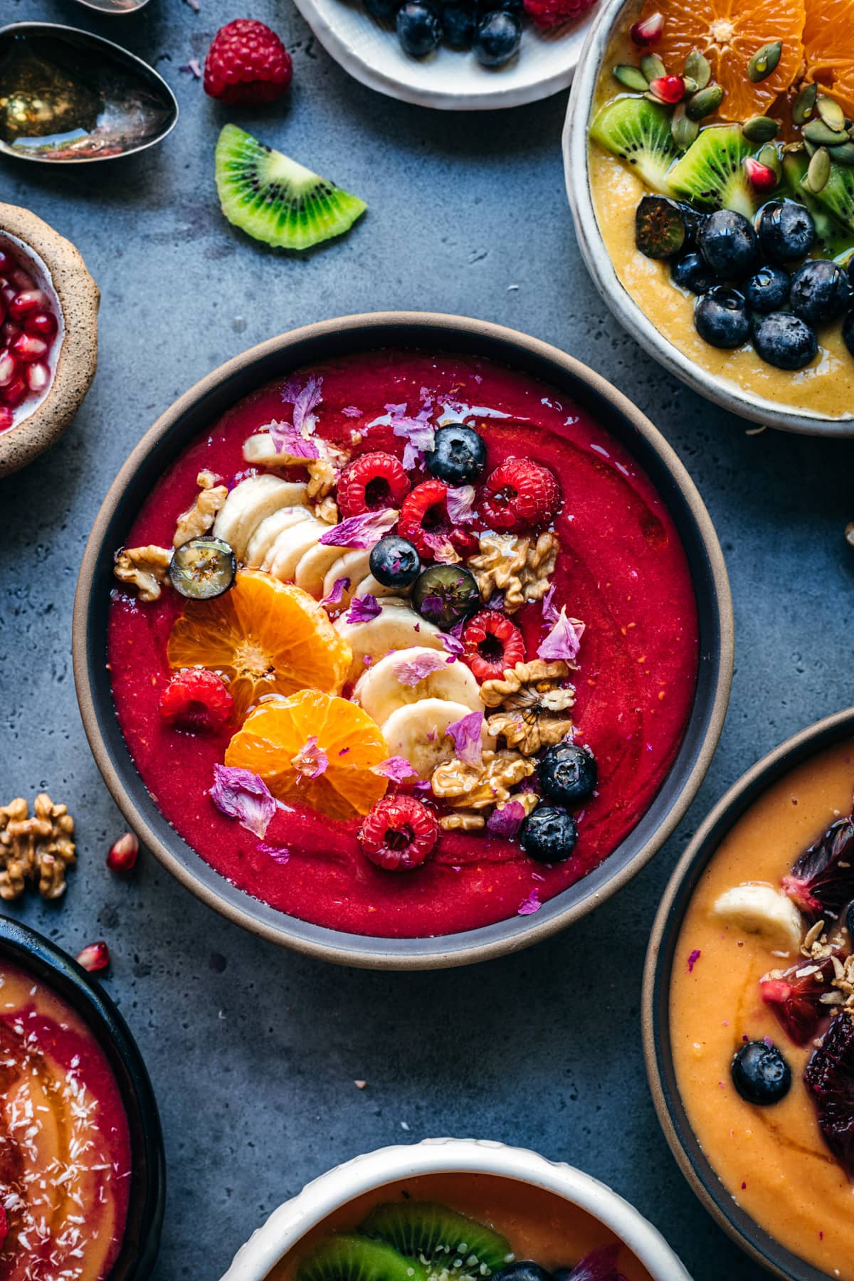 overhead view of berry ginger smoothie bowl topped with fresh fruit and nuts. 