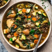 close up overhead view of lentil vegetable soup in a bowl with spoon.