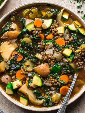 close up overhead view of lentil vegetable soup in a bowl with spoon.