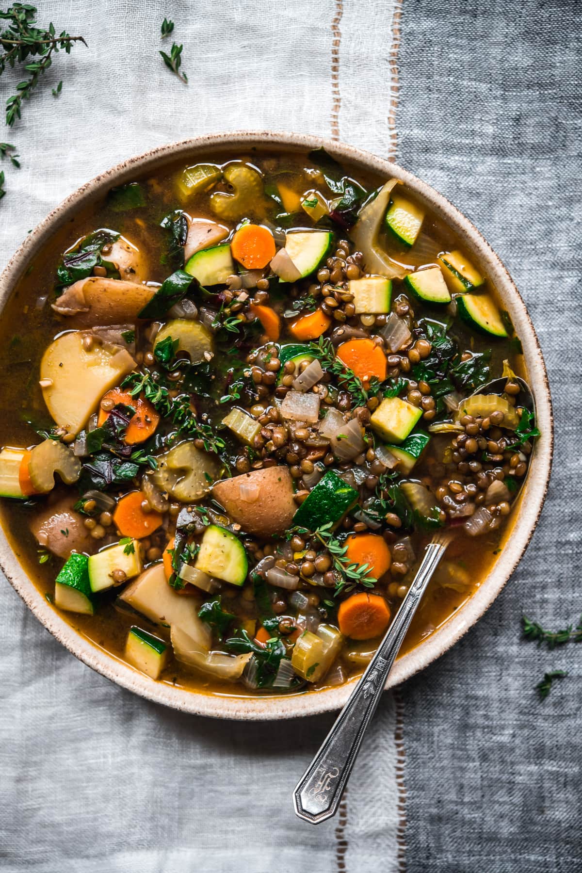 close up overhead view of lentil vegetable soup in a bowl with spoon.