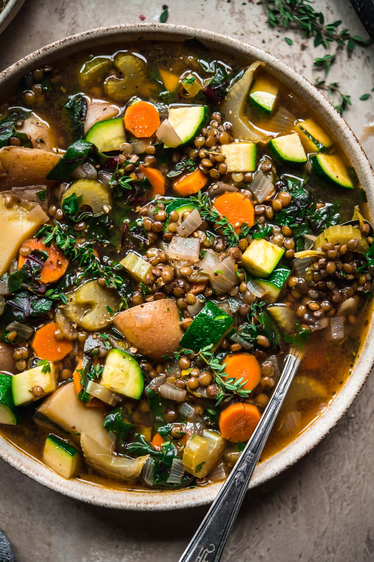 close up overhead view of lentil vegetable soup in a bowl with spoon.