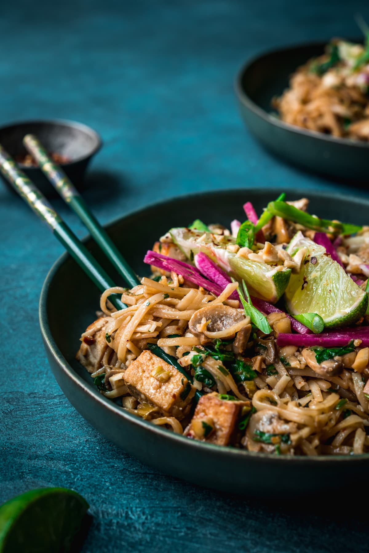 close up view of vegan pad thai with rice noodles, tofu and mushrooms.