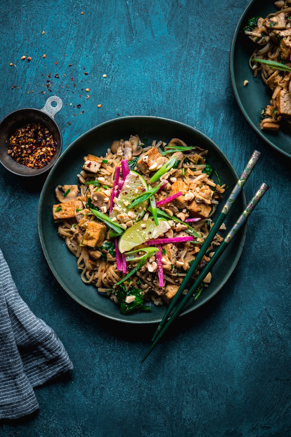 overhead view of vegan pad thai with tofu in a blue bowl with chopsticks.