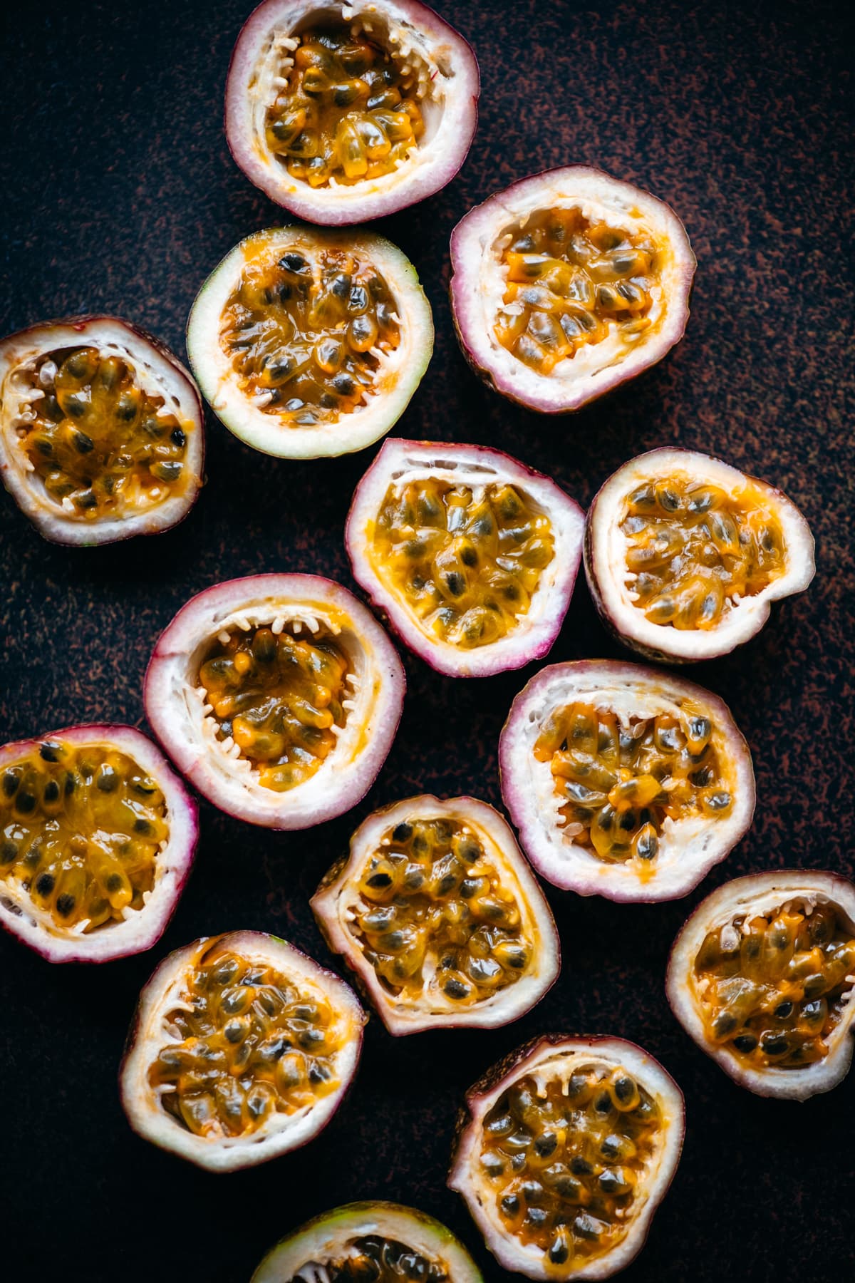 overhead view of fresh passion fruit halves on dark background. 