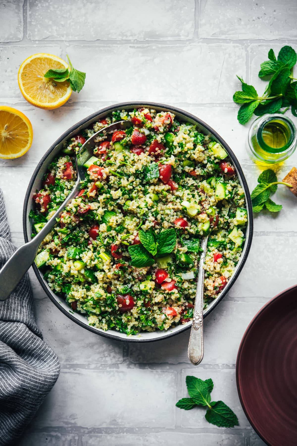 overhead view of vegan quinoa tabbouleh in a salad bowl with serving spoons. 